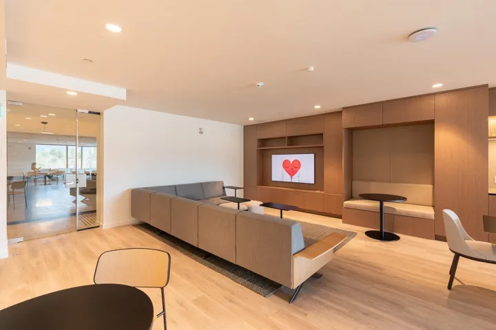 Spacious common area featuring light wood-finish flooring, recessed lighting, and a large built-in media console with storage