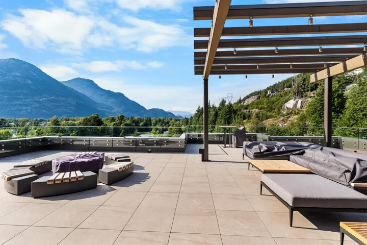 Expansive rooftop terrace featuring a tiled floor, glass perimeter railing, and a wood pergola