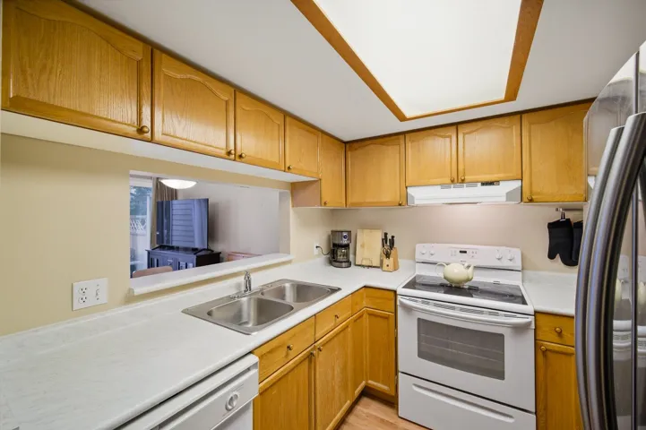 Kitchen featuring white appliances, light countertops, and wood finish cabinets