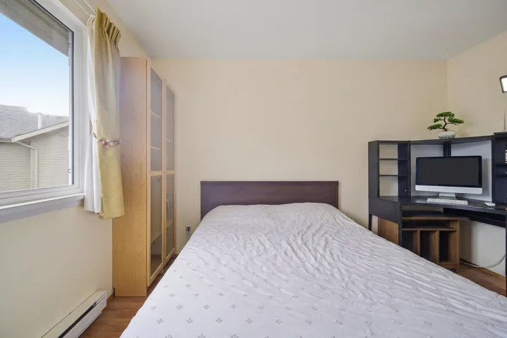 Bedroom with baseboard heating and wood finished floors