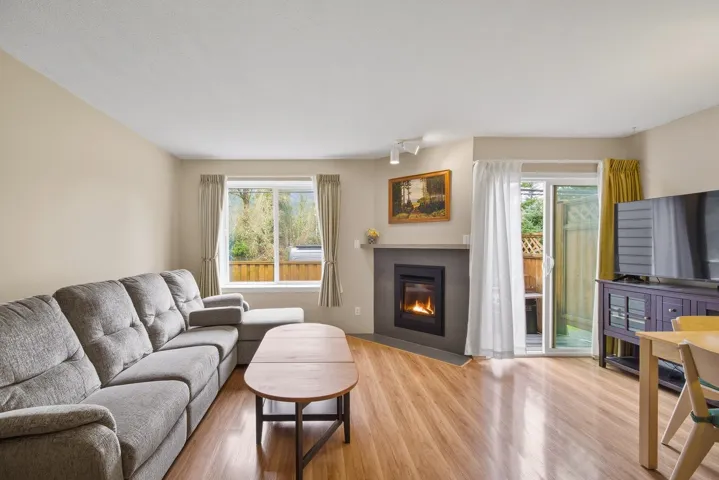 Living area featuring wood finished floors, healthy amount of natural light, and a fireplace with flush hearth