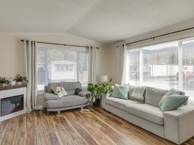 Living room with wood finished floors, crown molding, and a glass covered fireplace