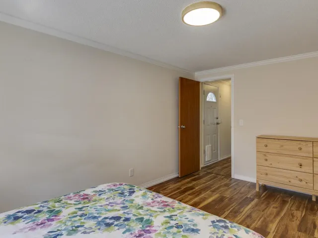 Bedroom featuring dark wood-style floors, crown molding, and a textured ceiling