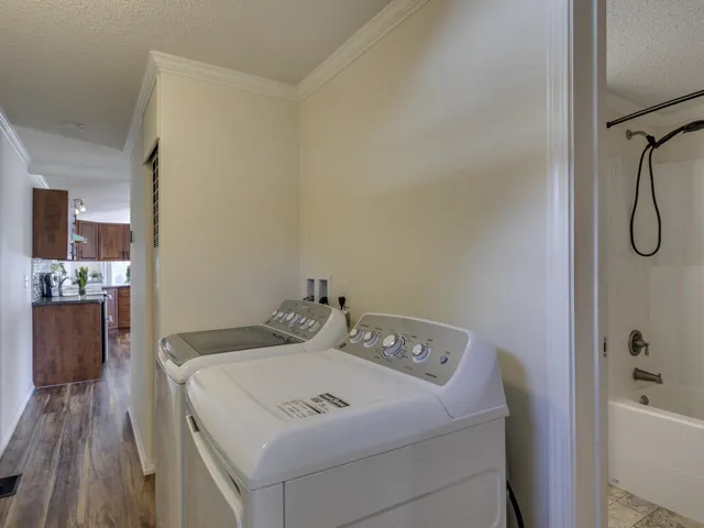 Laundry area with a textured ceiling, ornamental molding, and washer and clothes dryer