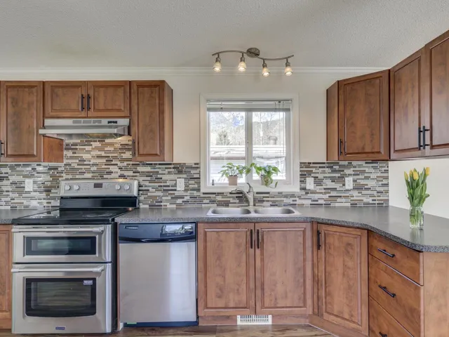 Kitchen featuring stainless steel appliances, wood finish cabinetry, a textured ceiling, and crown molding