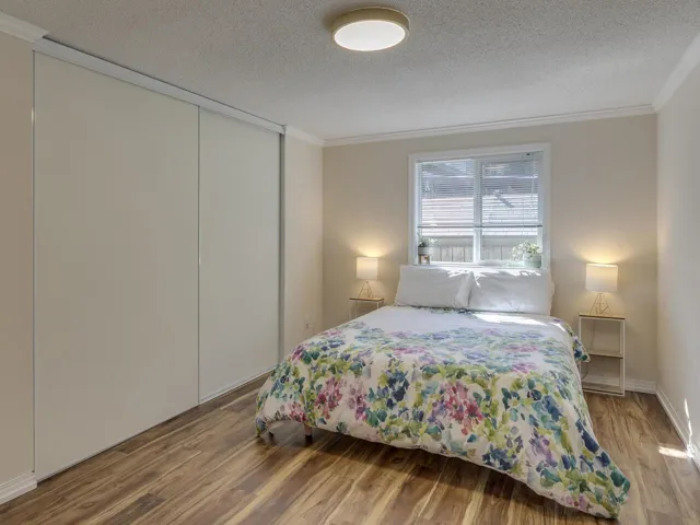 Bedroom with wood finished floors, a textured ceiling, crown molding, and a closet