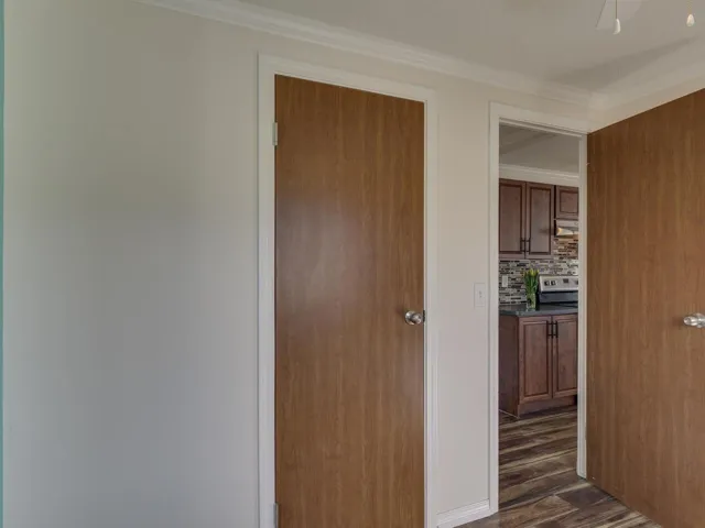 Hall with dark wood-type flooring and crown molding