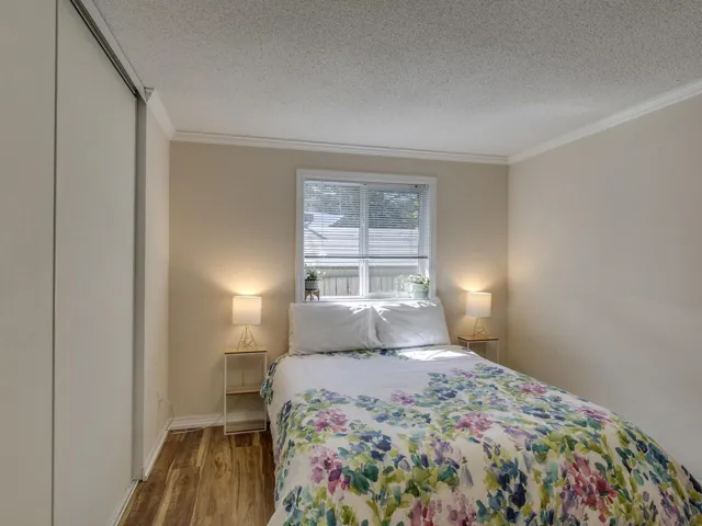 Bedroom with wood finished floors, ornamental molding, and a textured ceiling