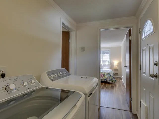 Laundry area featuring crown molding, a textured ceiling, dark wood finished floors, and washer and dryer