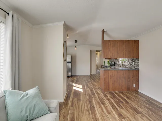 Kitchen featuring wood finish cabinetry, a peninsula, dark countertops, open floor plan, and lofted ceiling