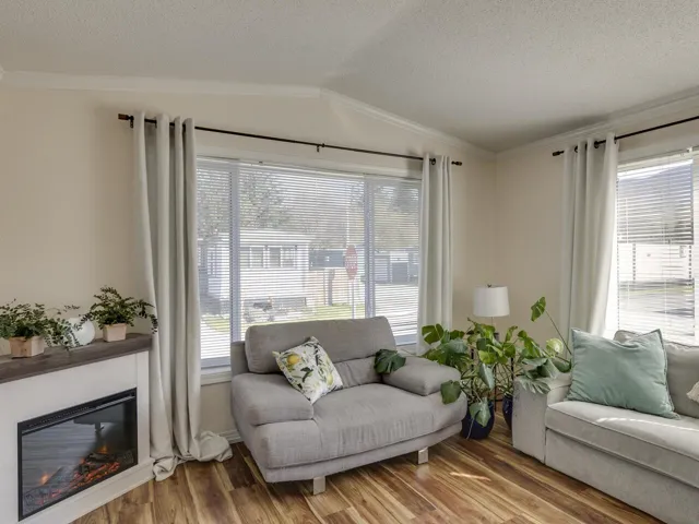 Living room with ornamental molding, a glass covered fireplace, wood finished floors, and healthy amount of natural light