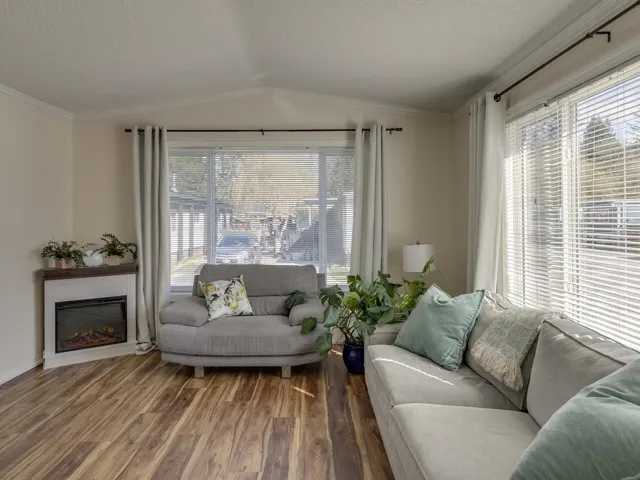 Living area with wood finished floors, ornamental molding, a glass covered fireplace, healthy amount of natural light, and a textured ceiling