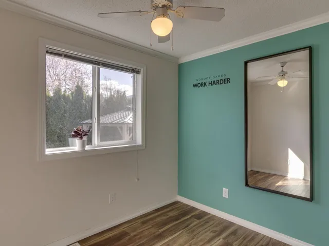 Empty room with a ceiling fan, dark wood-style floors, a textured ceiling, and crown molding