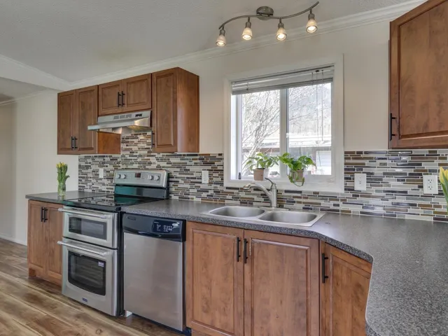 Kitchen with ornamental molding, stainless steel appliances, dark countertops, wood finish cabinetry, and a textured ceiling