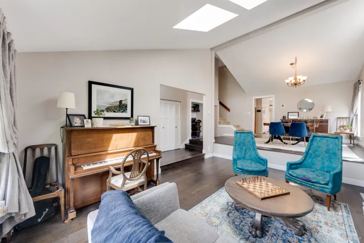 Living area with stairway, a chandelier, wood finished floors, high vaulted ceiling, and a skylight