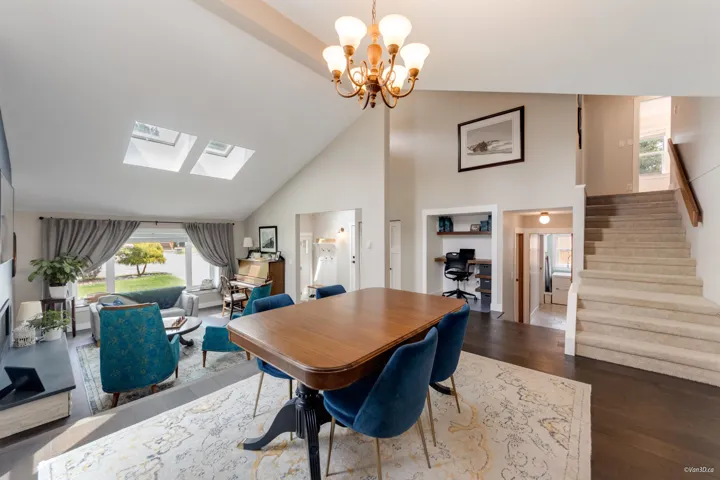 Dining room with a skylight, wood finished floors, high vaulted ceiling, stairs, and a chandelier