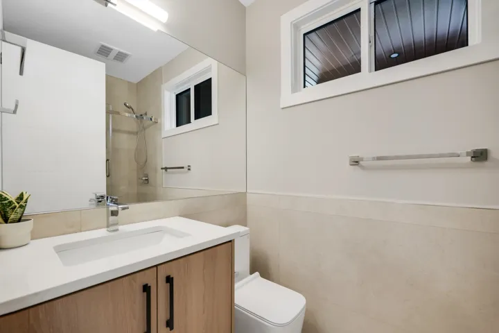Full bathroom featuring a shower stall, vanity, tile walls, and wainscoting