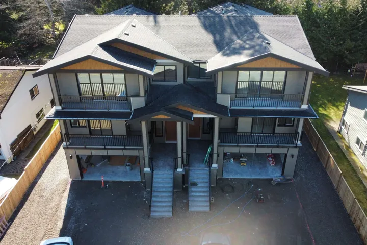 View of front facade featuring roof with shingles, a balcony, and a garage