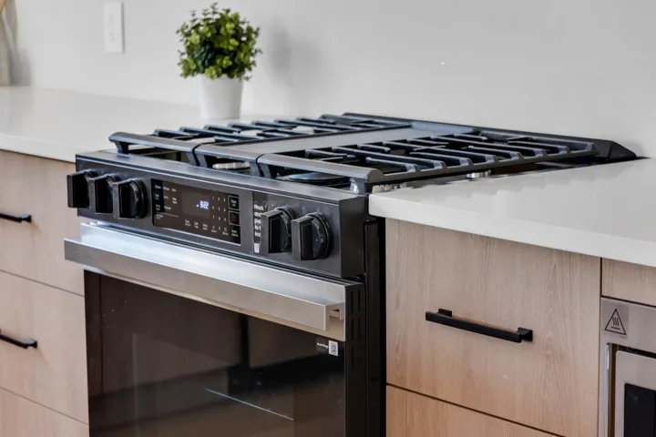 Kitchen view of light wood finish cabinets, range with gas cooktop, and modern cabinets