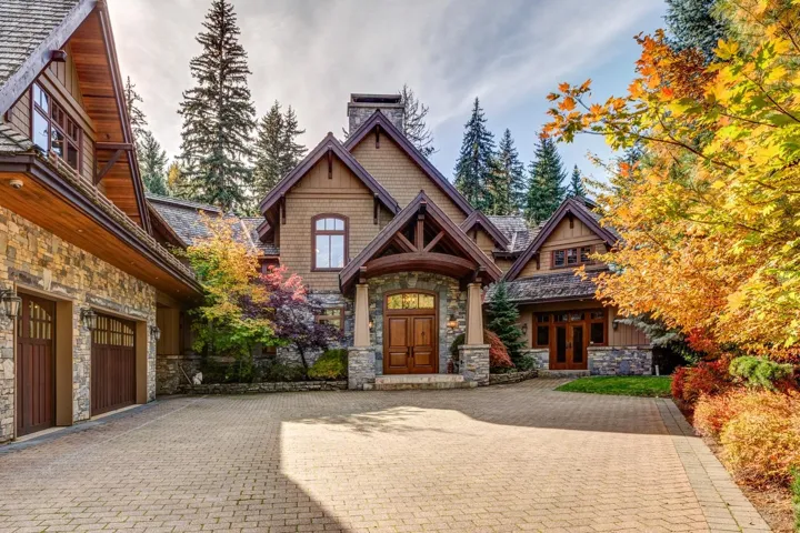 View of front of home featuring stone siding, a chimney, decorative driveway, and french doors