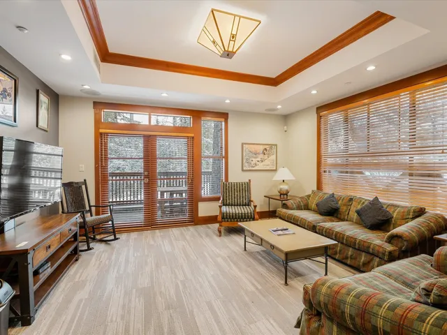 Living area featuring ornamental molding, a raised ceiling, and recessed lighting
