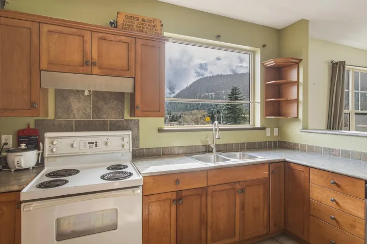 Kitchen with white range with electric cooktop, wood finish cabinets, a mountain view, light countertops, and open shelves