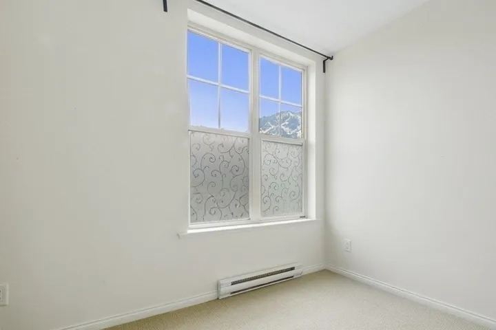 Unfurnished room with baseboard heating and light colored carpet
