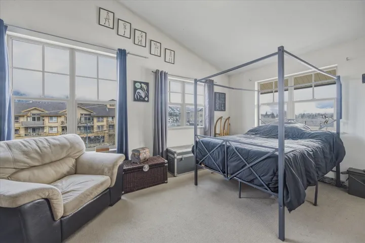 Bedroom with light colored carpet and vaulted ceiling