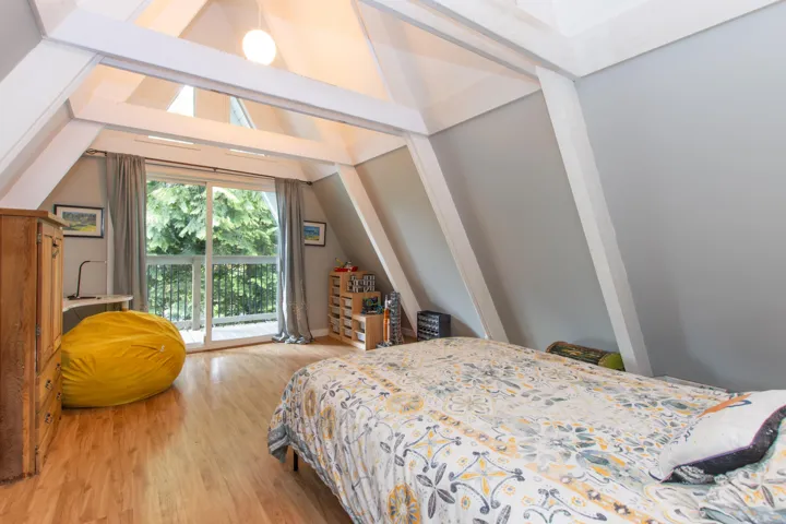 Bedroom with access to exterior, lofted ceiling, and wood finished floors