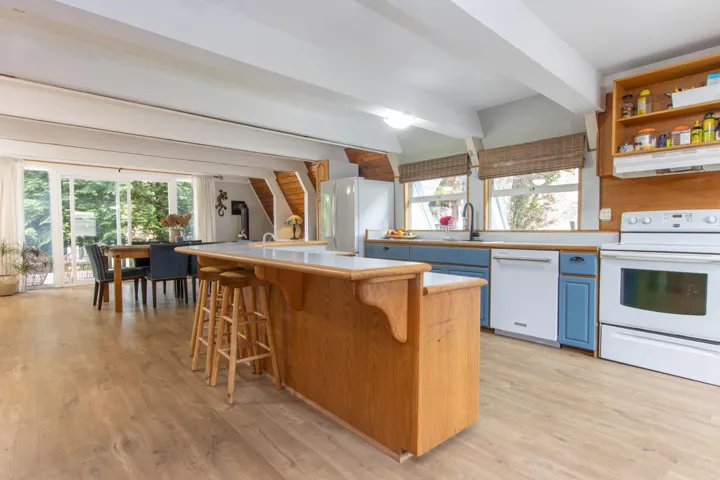 Kitchen featuring white appliances, under cabinet range hood, blue cabinetry, a breakfast bar, and light wood-style floors