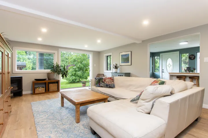 Living room loaded with natural light, light wood-style floors, and recessed lighting and gas fireplace.