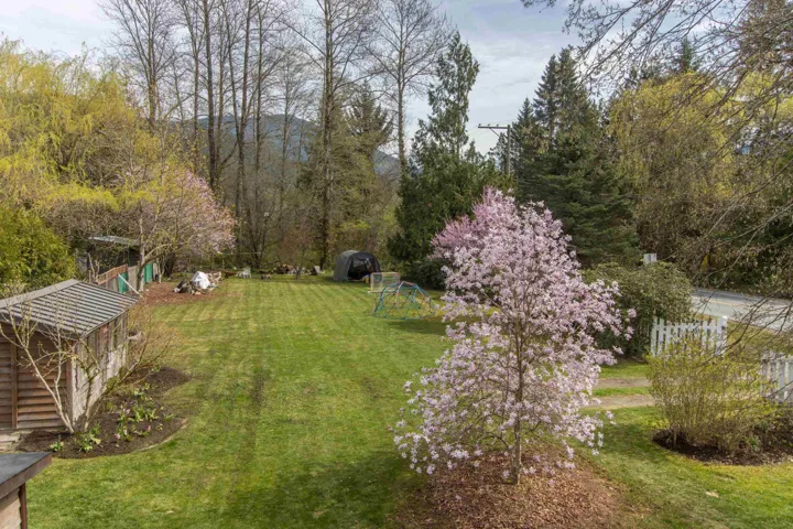 View of grassy yard featuring 2x freestanding storage sheds