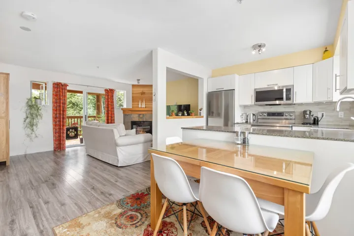 Kitchen featuring stainless steel appliances, stone counters, a tile fireplace, white cabinets, and backsplash