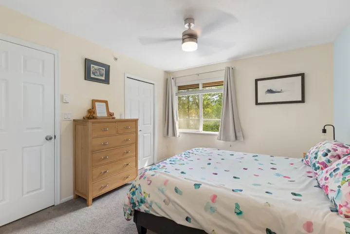 Bedroom with light carpet, a closet, and a ceiling fan