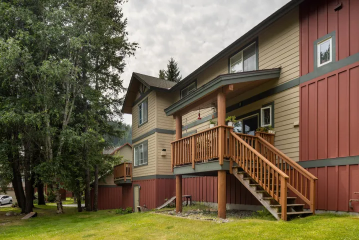 Rear view of house featuring stairway, a lawn, a porch, and board and batten siding