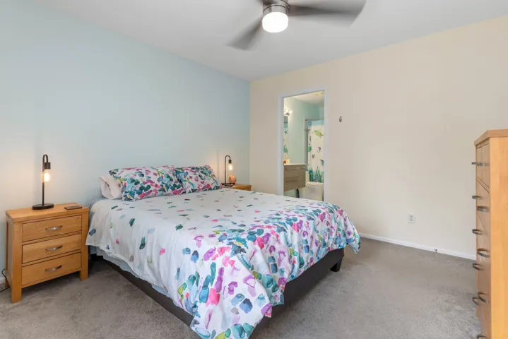 Bedroom with carpet flooring, ensuite bath, and ceiling fan