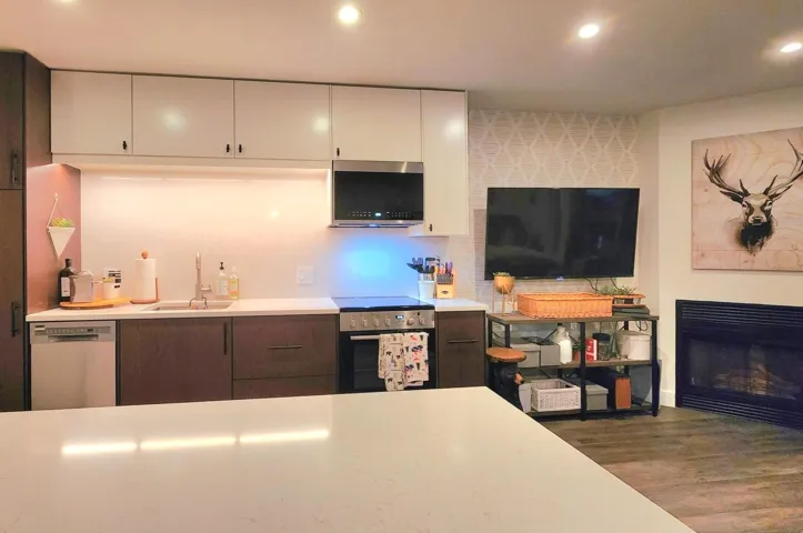 Kitchen with white cabinets, a sink, stainless steel appliances, light countertops, and wood finished floors