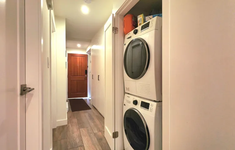 Laundry room with recessed lighting, wood finished floors, stacked washer and dryer, and laundry area
