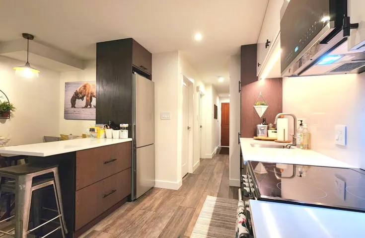 Kitchen with a sink, appliances with stainless steel finishes, light countertops, light wood finished floors, and a peninsula