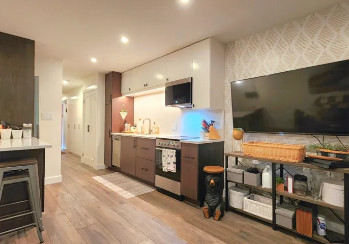 Kitchen with recessed lighting, light wood-style flooring, stainless steel appliances, light countertops, and a sink
