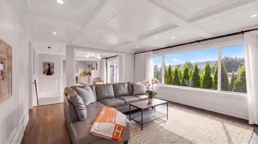 Spacious living area featuring large picture windows, dark wood-finish flooring, coffered ceiling, and recessed lighting