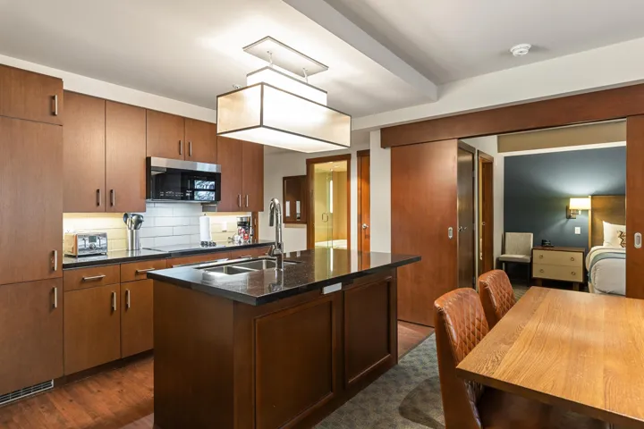 Kitchen with a center island with sink, dark wood finished floors, a sink, stainless steel microwave, and tasteful backsplash