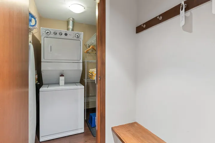 Clothes washing area featuring stacked washer / drying machine and wood finished floors