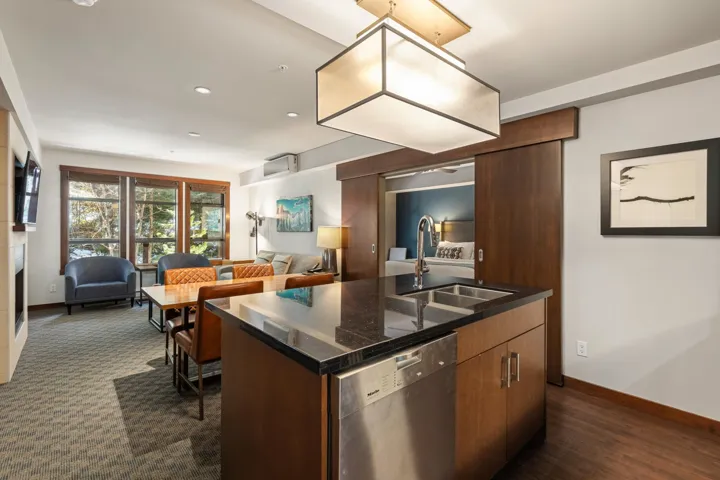 Kitchen featuring dark countertops, a sink, open floor plan, and stainless steel dishwasher