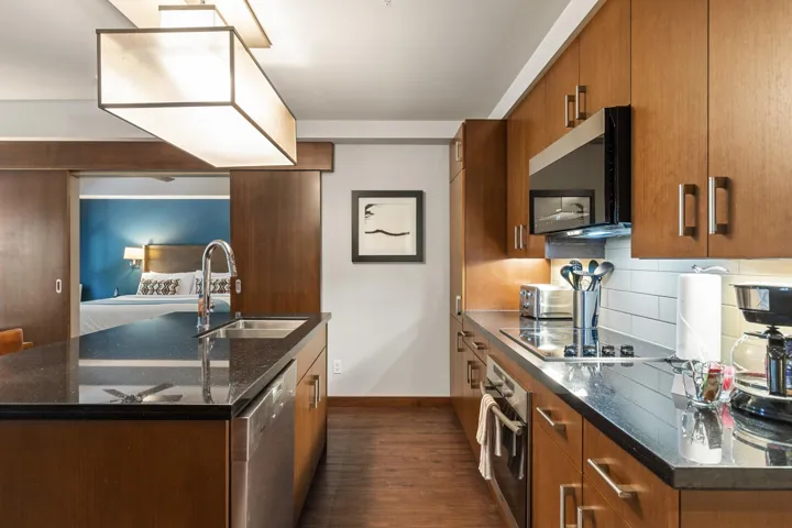 Kitchen with brown cabinets, dark wood-type flooring, a sink, tasteful backsplash, and appliances with stainless steel finishes