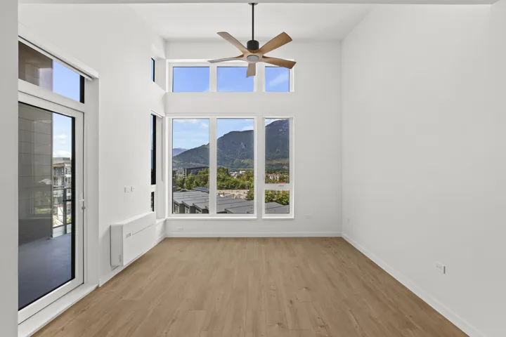 Unfurnished room featuring a mountain view, a ceiling fan, light wood-type flooring, plenty of natural light, and a towering ceiling