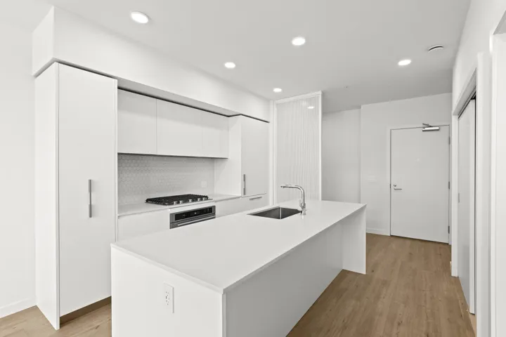 Kitchen featuring modern cabinets, white cabinets, backsplash, recessed lighting, and light countertops