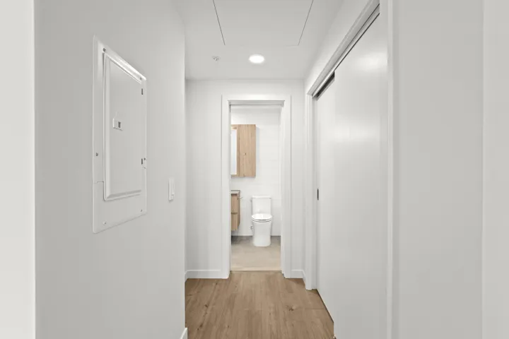Corridor featuring light wood-type flooring, electric panel, attic access, and recessed lighting