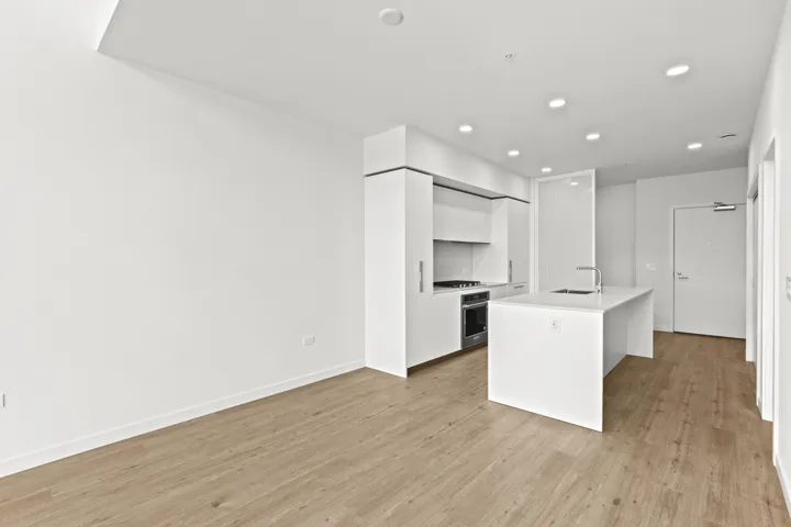 Kitchen with white cabinetry, light wood finished floors, light countertops, a kitchen island with sink, and appliances with stainless steel finishes