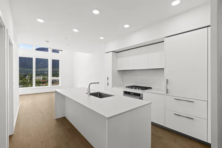 Kitchen with modern cabinets, recessed lighting, white cabinetry, dark wood-style flooring, and a kitchen island with sink